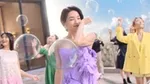 身穿色彩鮮豔的洋裝和套裝的女性們置身於戶外巨大的半透明泡泡之中。