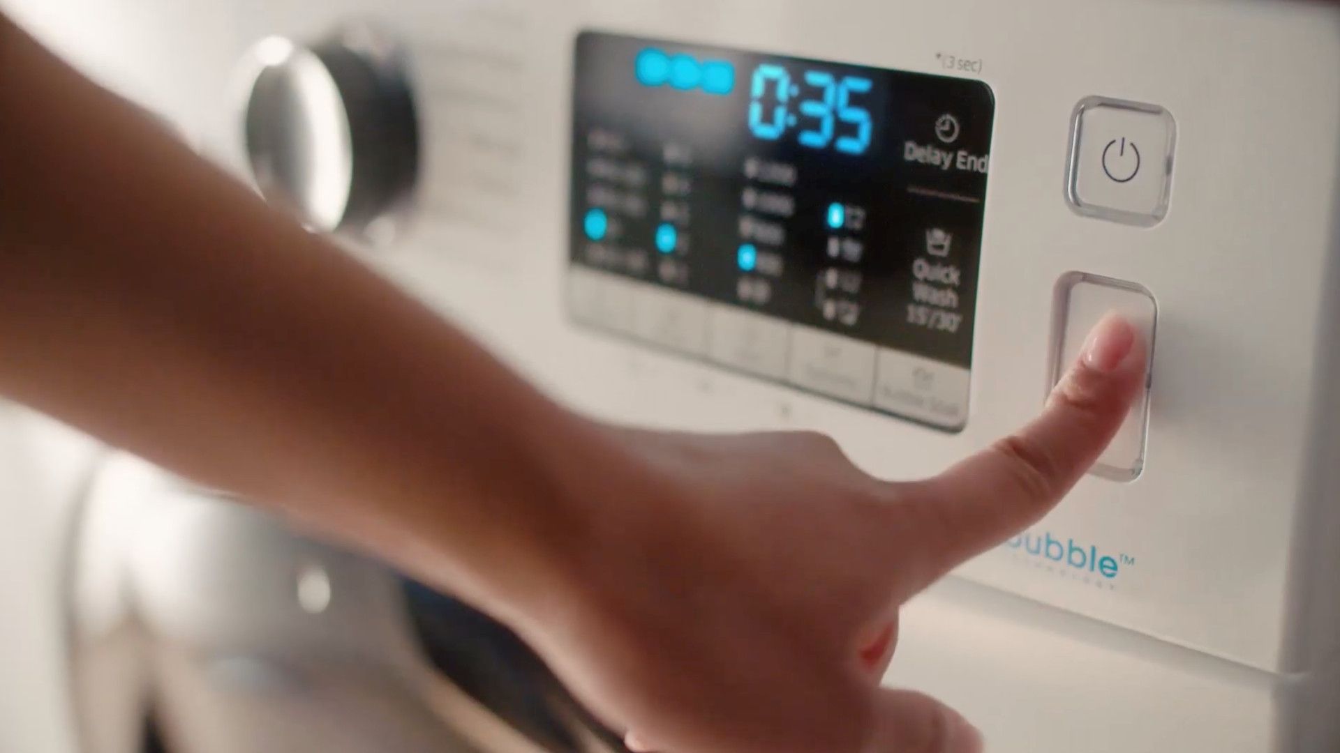 用手按下洗衣機的啟動按鈕，數位顯示器顯示剩餘時間 0:35 分鐘。